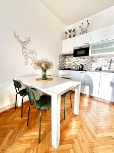 uma cozinha branca com uma mesa e cadeiras brancas em Bright and central suite with a balcony em Brno