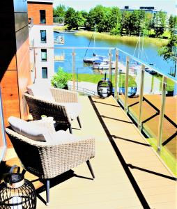a balcony with chairs and a table and a view of a river at Marina Glamour Apartment plus parking w hali in Iława