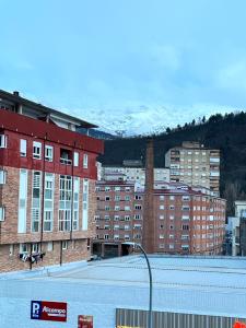 un aparcamiento con edificios y una montaña cubierta de nieve en El descanso de la Covatilla, en Béjar