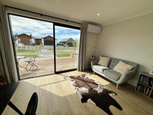 een woonkamer met een bank en een grote glazen schuifdeur bij Whiti Te Ra 1 Bed in Lake Tekapo