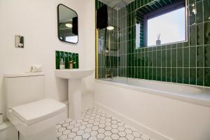 a bathroom with a sink toilet and green tiles at Newcastle City Apartments - FREE Parking Baltic Quay in Gateshead