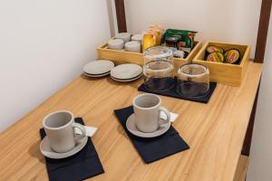 une table avec deux tasses et des assiettes dessus dans l'établissement Case Varanni Etna Experience, à Viagrande