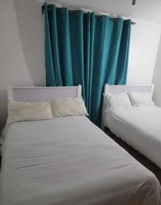 2 Betten in einem Zimmer mit grünem Vorhang in der Unterkunft Jbl homes in Ruaka
