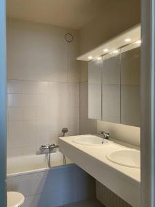 ein Badezimmer mit zwei Waschbecken und einer Badewanne und einem Spiegel in der Unterkunft Mooi appartement met zijdelings zeezicht, op 100 meter van strand in Knokke-Heist