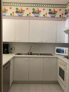 eine Küche mit weißen Schränken und einer Spüle und einer Mikrowelle in der Unterkunft Mooi appartement met zijdelings zeezicht, op 100 meter van strand in Knokke-Heist