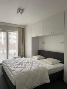 ein Schlafzimmer mit einem großen weißen Bett mit einem Fenster in der Unterkunft Mooi appartement met zijdelings zeezicht, op 100 meter van strand in Knokke-Heist