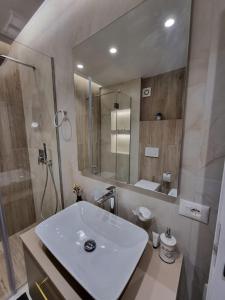a white bathroom with a sink and a shower at Central Continental Apartment in Tirana