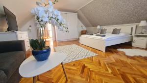 uma sala de estar com uma cama e uma mesa com um vaso de flores em Lugas Apartman em Villány