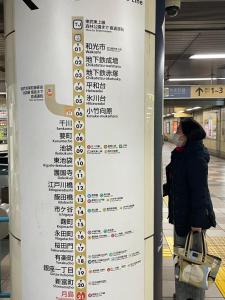a woman standing next to a sign at a subway station at 平安旅馆和风 in Tokyo