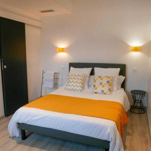 a bedroom with a large bed with an orange blanket at LE CENTRAL HOTEL BAR RESTAURANT in Balaruc-les-Bains