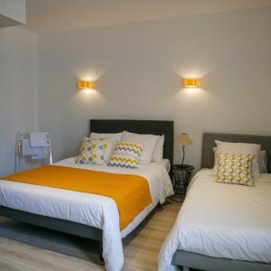 Un dormitorio con dos camas y dos luces en la pared. en LE CENTRAL HOTEL BAR RESTAURANT, en Balaruc-les-Bains