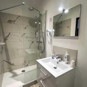Un baño con lavabo y ducha de cristal. en LE CENTRAL HOTEL BAR RESTAURANT, en Balaruc-les-Bains