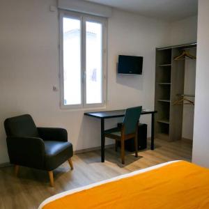 Habitación con escritorio, silla y TV. en LE CENTRAL HOTEL BAR RESTAURANT, en Balaruc-les-Bains