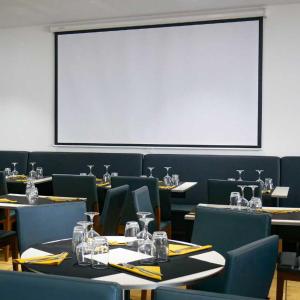uma sala de jantar com mesas e cadeiras e um grande ecrã em LE CENTRAL HOTEL BAR RESTAURANT em Balaruc-les-Bains