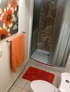 El baño incluye ducha y aseo con toalla de color naranja. en Habitación Doble Mayan Plaza en Copan Ruinas