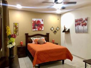 een slaapkamer met een bed met een oranje deken bij Habitación Doble Mayan Plaza in Copan Ruinas