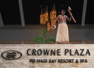 Una estatua de un hombre parado sobre una señal en Crowne Plaza Fiji Nadi Bay Resort & Spa, an IHG Hotel en Nadi