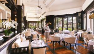 a restaurant with white tables and chairs and a waiter at InterContinental Bali Resort by IHG in Jimbaran