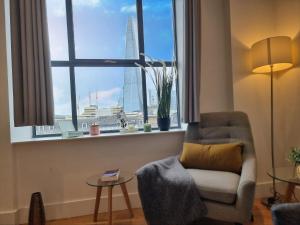 a living room with a chair and a large window at Shard View Apartments in London