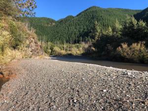 a river with a bunch of rocks next to a mountain at The River Shack in Nelson