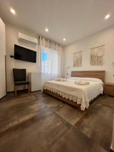 Schlafzimmer mit einem Bett, einem TV und einem Stuhl in der Unterkunft B&B Hakuna Matata in Alghero