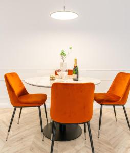 a dining room table with orange chairs and a bottle of champagne at Lake Apart in Iława
