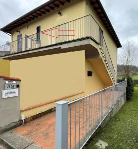 ein gelbes Gebäude mit einem Balkon und einem Zaun in der Unterkunft Ma maison jolie in Incisa in Valdarno