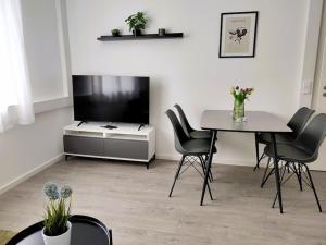 a living room with a tv and a table and chairs at Modernes zentrales Apartment in Bruchsal