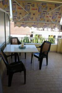 a table and chairs with a coffee cup on a balcony at Koletsis Rooms (Villa Koletsis) in Ammoudia