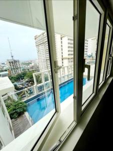 uma vista para uma piscina a partir de uma janela em High speed internet - Cozy 1BR fully Furnished em Manila