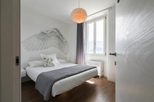 a white bedroom with a bed and a window at NELL'A COMO in Griante Cadenabbia