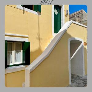 a yellow building with a white stairway next to a window at Pozzo House Corfu - Traditional House for 3 near Agios Georgios Beach in Argyrádes