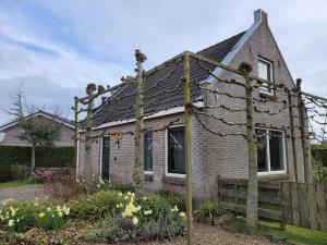 une vieille maison en briques avec une clôture et des fleurs dans l'établissement Holiday Home Friesland near the Wadden Sea with Wifi and 3 Bedrooms, à Tzummarum