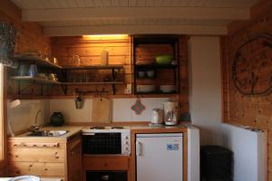 eine kleine Küche mit Holzschränken und einem weißen Kühlschrank in der Unterkunft Åkviktunet hytte nord in Averoy