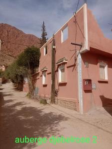 a pink house with a mountain in the background at auberge djebel rose 2 in Tafraoute