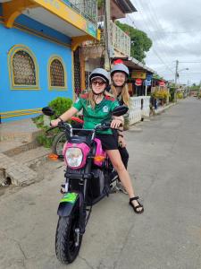 Dwie dziewczyny siedzące na motocyklu na ulicy w obiekcie Guest House Nena w mieście Moyogalpa