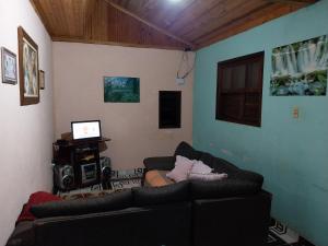 sala de estar con sofá y TV en Hospedagem Manacás, en Alagoa