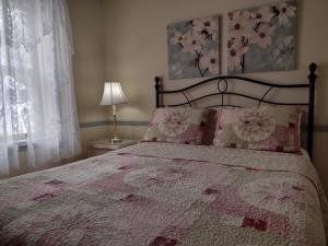 - une chambre avec un lit doté d'une couverture rose et d'une fenêtre dans l'établissement Chez Rose Belaid, à Percé