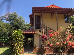 une maison avec balcon et quelques fleurs dans l'établissement Chácara Aconchego, à Três Marias