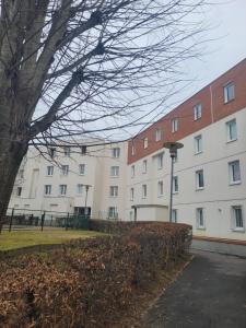 a large white building with a tree in front of it at Appartement T4 J024 - 5 min de marche VTT -10 min Vélodrome dans résidence agréable 6 pers in Élancourt