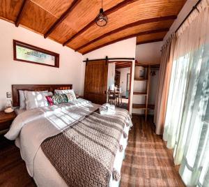 sypialnia z dużym łóżkiem i drewnianym sufitem w obiekcie Cabañas Boutique Faldeos de La Lajuela w mieście Santa Cruz