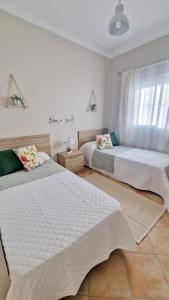 1 dormitorio con 2 camas y ventana en Villas Luins, en Chiclana de la Frontera