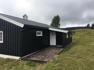 een zwart gebouw met een houten terras op een heuvel bij Einkjerrbu cabin by Norgesbooking - in Svingvoll