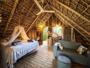 a bedroom with a bed and a couch in a cabin at Bungalows India & boutique, El Valle, Samana in Santa Bárbara de Samaná