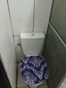 a bathroom with a toilet with a blue and white toilet seat at Hotel Pousada Roma in Caràzinho