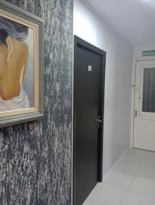 a door in a hallway with a painting on the wall at Hotel Pousada Roma in Caràzinho