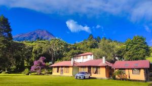 a house with a car parked in a yard with a mountain at Orquideas Runtun in Baños