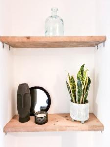 uma prateleira de madeira com uma garrafa de vidro e uma planta em 4-Bedroom home - Perfect for those working in Bridgend - By Tailored Accommodation em Bridgend