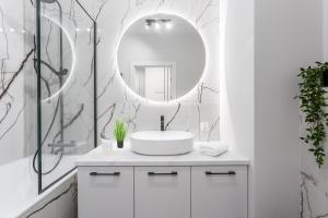 W białej łazience znajduje się umywalka i lustro. w obiekcie Warsaw View Prestige Apartment w Warszawie