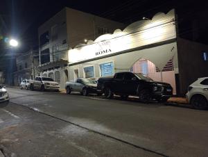 une rangée de voitures garées devant un bâtiment dans l'établissement Hotel Pousada Roma, à Caràzinho